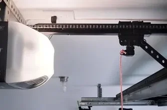 A white garage door opener mounted on its rail, with a red emergency release cord hanging down.