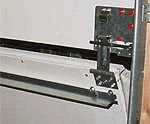 Close view of the break-away bottom section hardware at the edge of a commercial door.