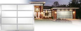 Clopay AVANTE™ Collection: A frosted glass and aluminum door, beside a contemporary house lit at dusk.