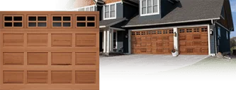 Clopay CLASSIC™ WOOD Collection: A wood raised-panel door with a row of windows, beside a dark blue house with a matching double door.