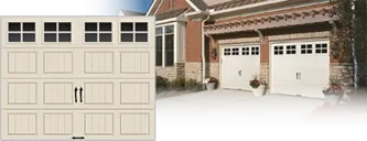 Clopay GALLERY® Collection: A cream carriage house door with square windows and black handles, beside a brick house with two matching doors.