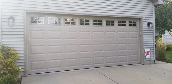The same house with a tan double door that has a row of small windows across the top section.