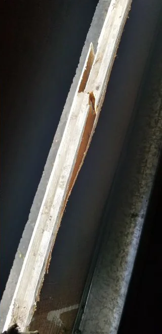 Close view of a long wooden edge that has split and splintered.